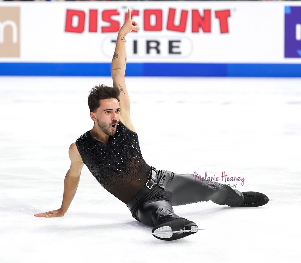 A figure skater dressed in black slides across the ice