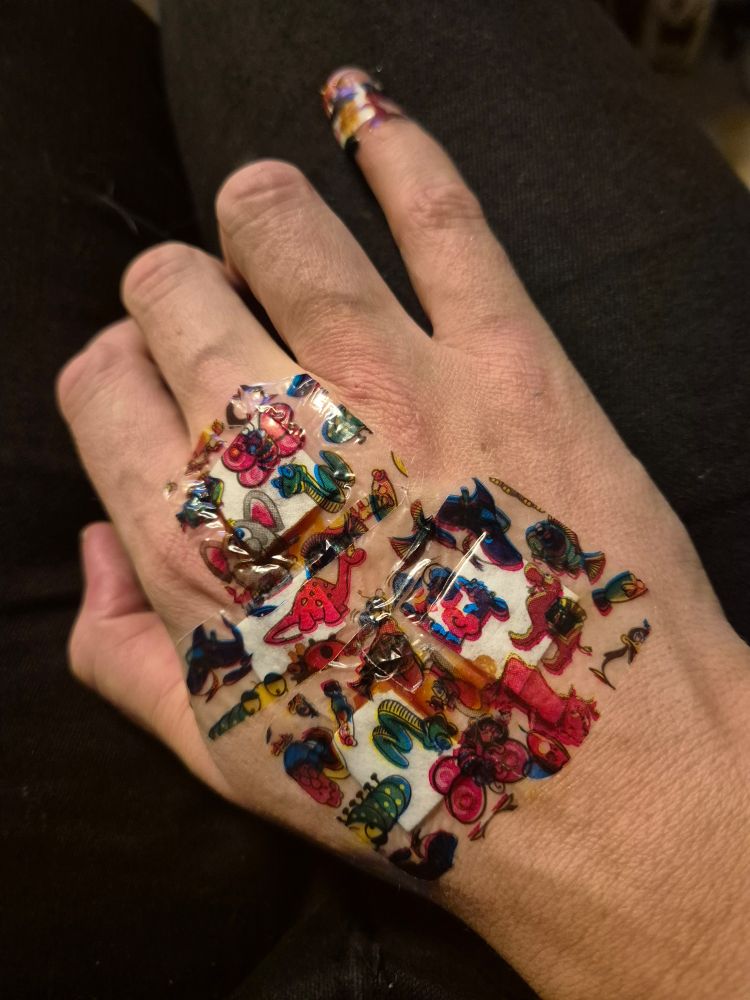 Eine Hand die mit vielen bunten Kinder Pflastern beklebt ist.