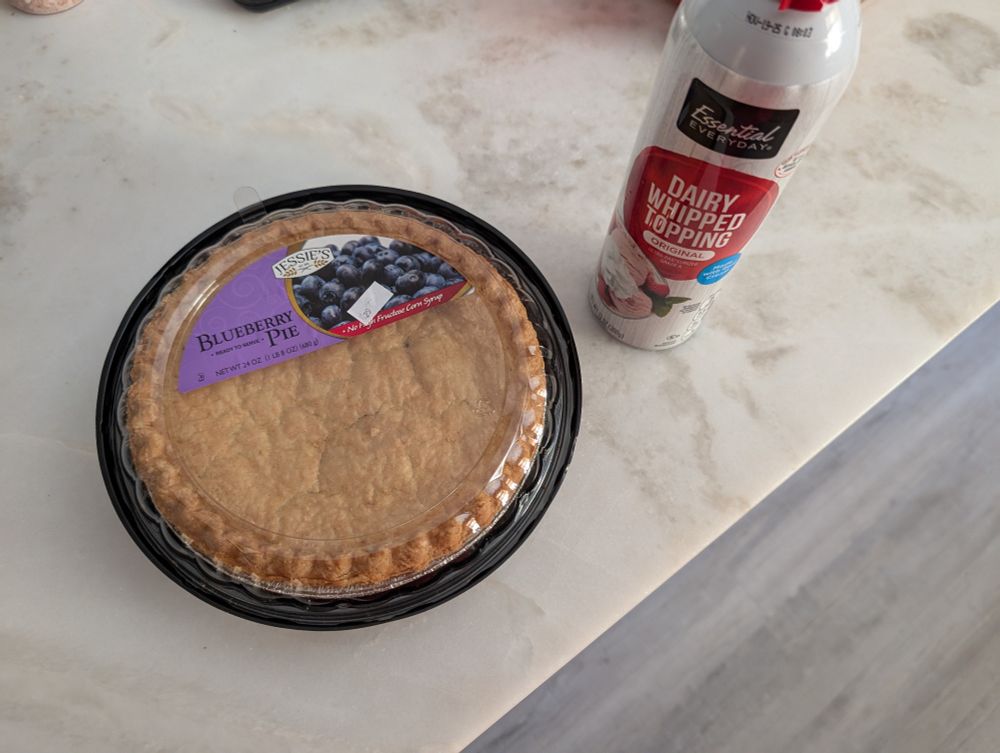 A premade blueberry pie and a can of whipped cream sitting on the counter