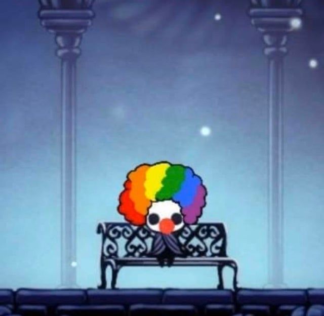 Protagonist of Hollow Knight wearing a colorful clown wig and nose, sitting at a bench 
