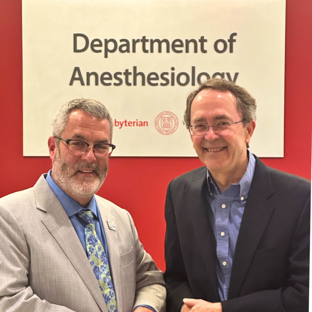 Dr. Warren Sandberg and Dr. Hugh Hemmings smiling at the camera in front of the Weill Cornell Medicine Department of Anesthesiology sign.