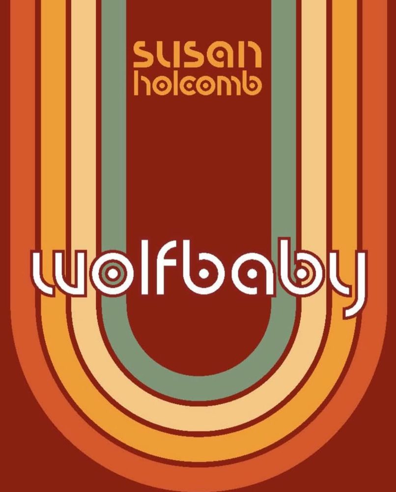 The book cover of Wolfbaby by Susan Holcomb. Shades of orange and a stripe of green form an inverted rainbow that covers the book. 
