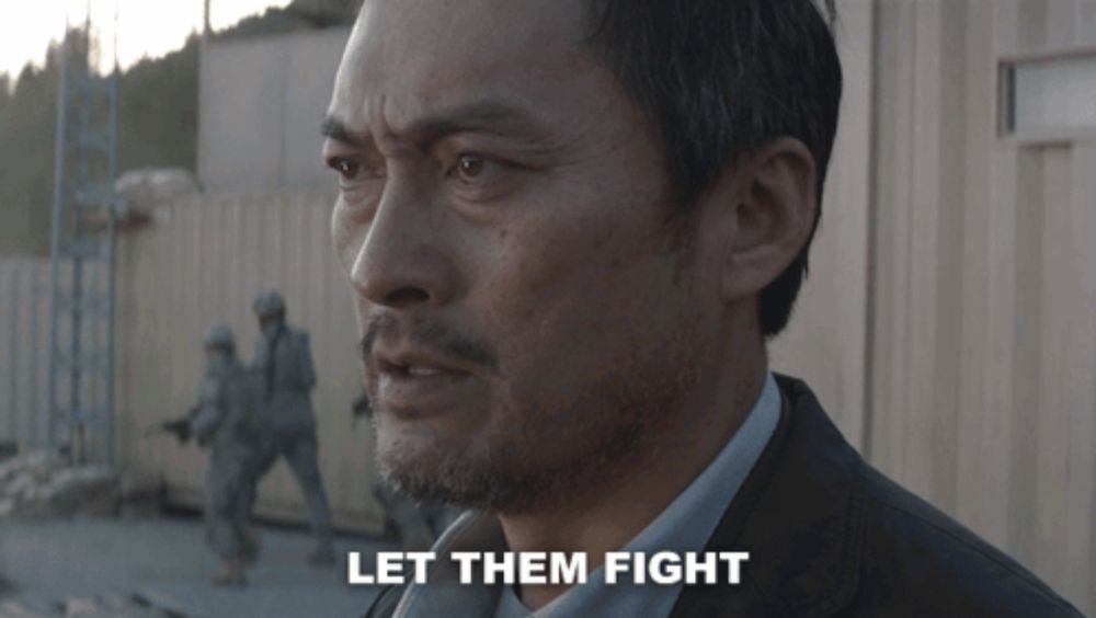 a man in a suit says let them fight in front of a group of soldiers