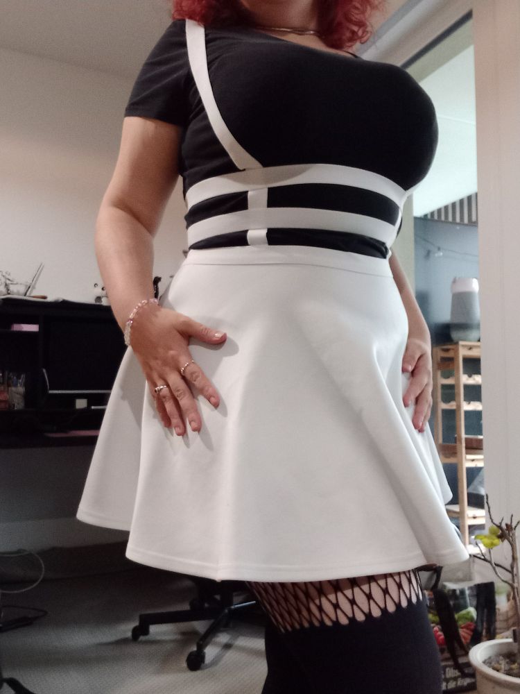 Picture of a body without face, wearing a white bib dress with a black shirt underneath