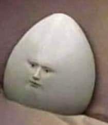 A grainy photo of an egg with a small face in the center. The egg is staring into the distance despondently.