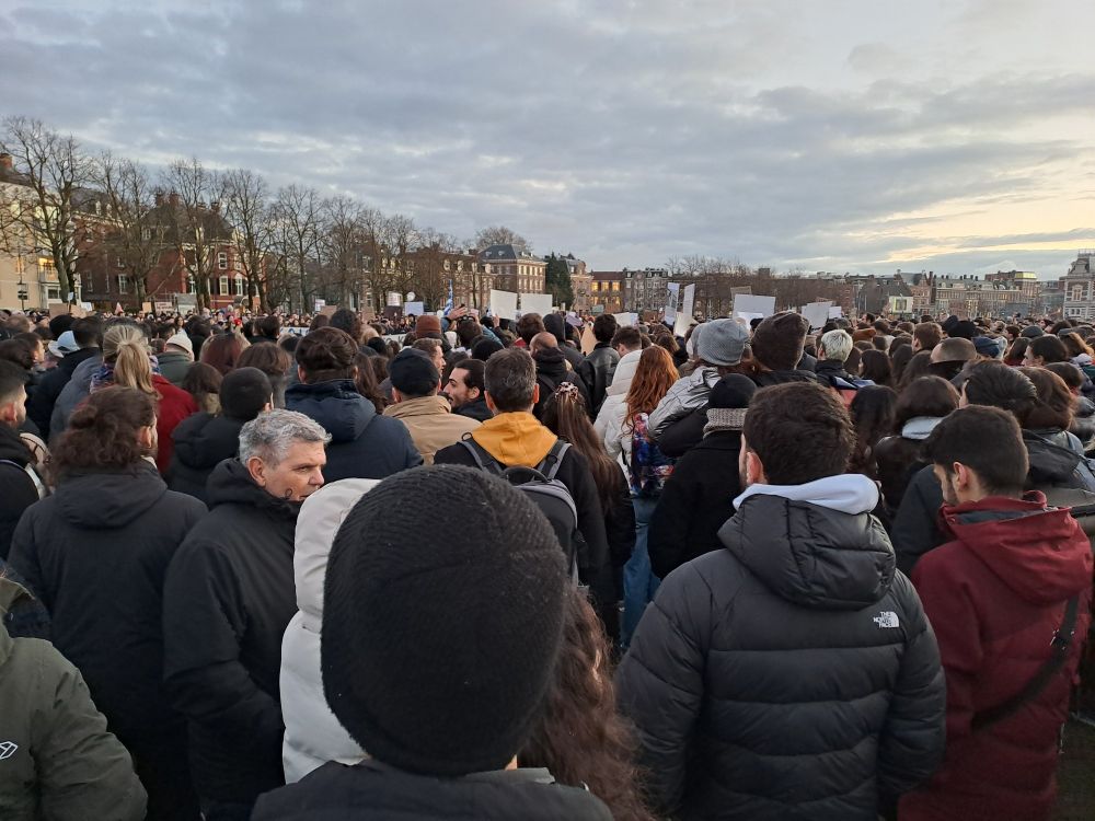 Gathering of people in Museum square in Amsterdam. Some playcard signs in the background