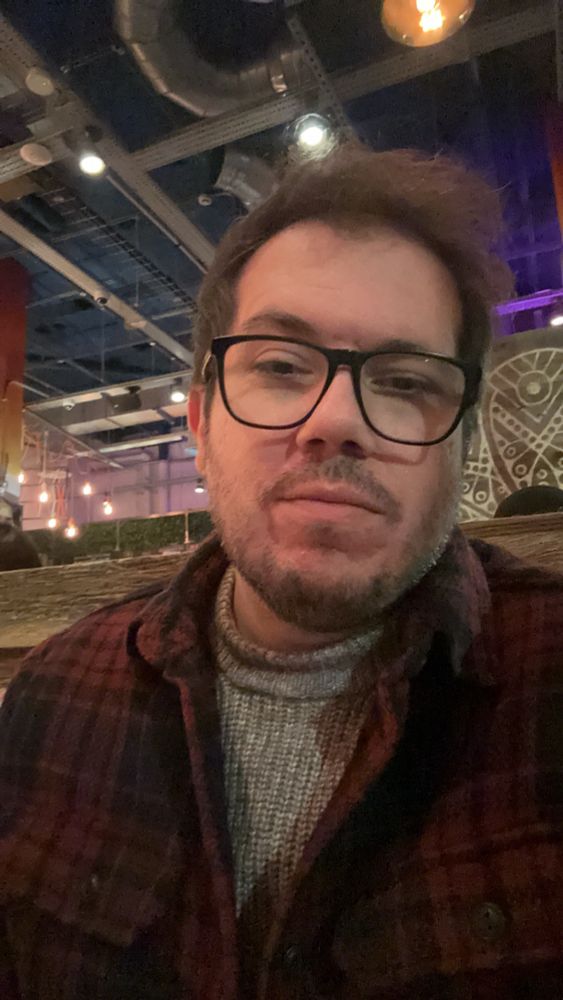 Selfie with a red checked jacket, jumper sat in a restaurant