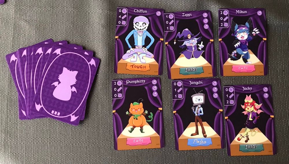 Examples of the monster card in the game Beautiful Monsters. It shows Chiffon, Zeppi, Mikun, Pumpkitty, Jangchi, and Jacky, next to some flipped over cards splayed out on the left to show what the backside of the cards looks like.