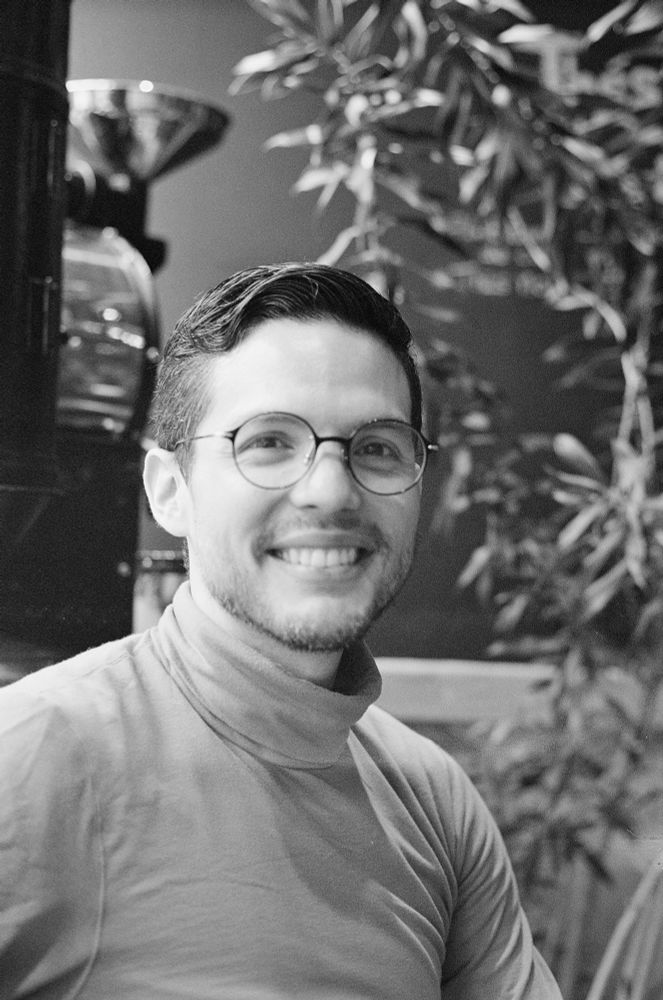 Black and white picture of me wearing a turtleneck and glasses. I’m smiling to the camera. 