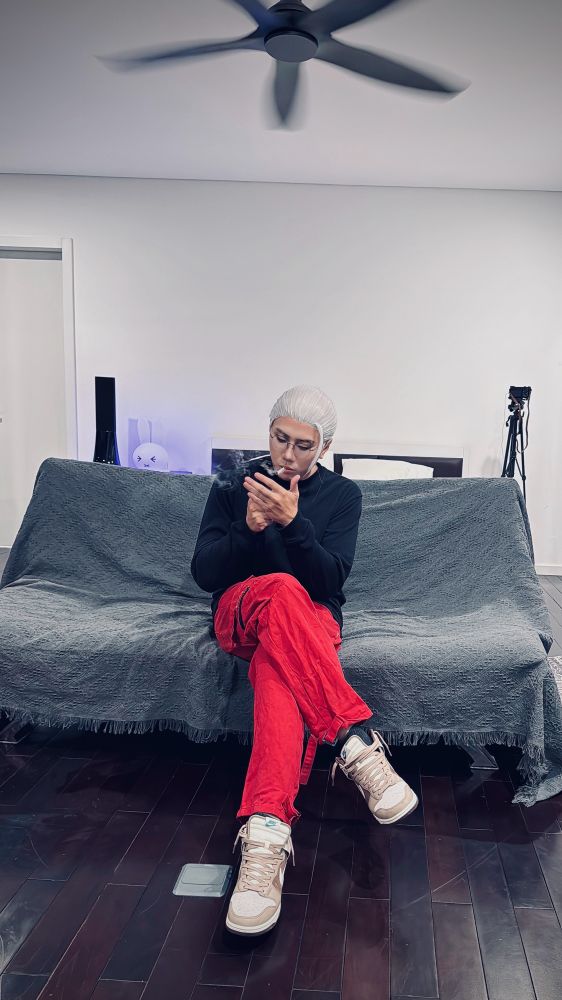 Toru Sakamoto sitting on a couch and lighting a cigarette. 