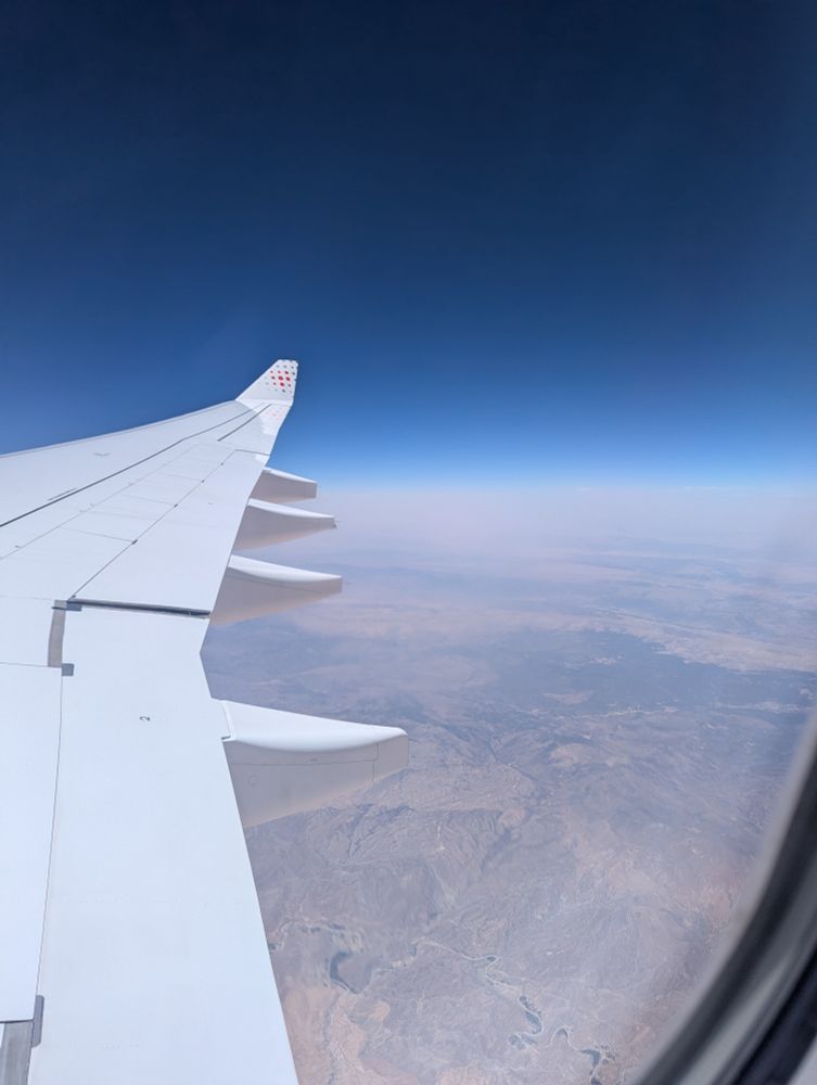 An aerial view of the Sahara desert with an airplane wing visible.