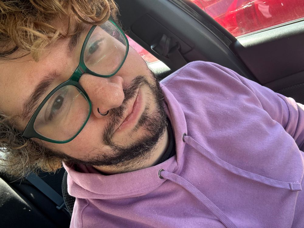 Beemz in a car wearing a lavender hoodie. It’s their husbands hoodie and this was quickly snapped to show that they stole it from their husband.