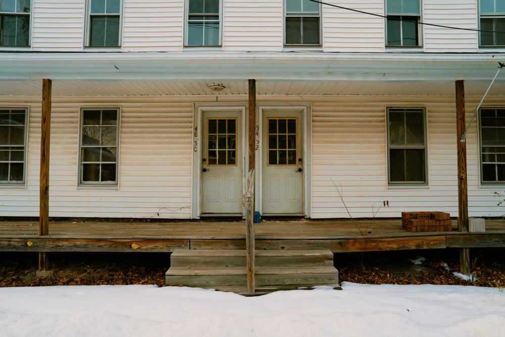 Color photo of the front porch of a duplex with the front doors and steps centered in the frame. 