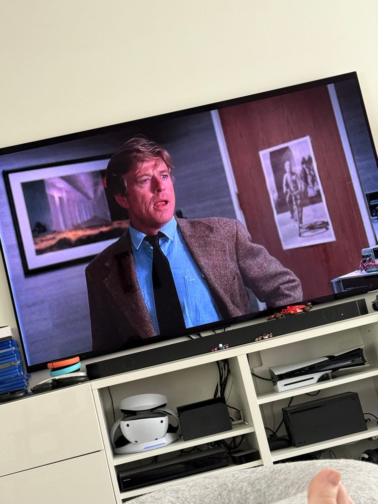 A scene shot from Robert Redford’s  film, Sneakers. The image has Redford’s character, Martin Bishop looking a little stressed (while wearing a brown suit and blue shirt)