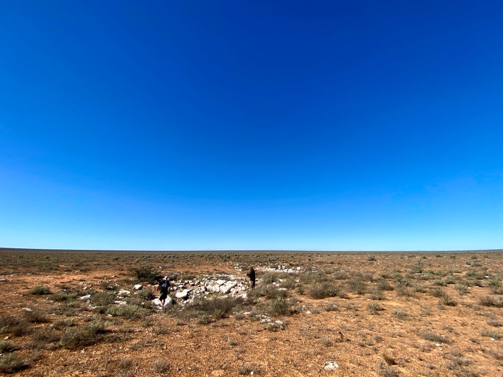A vast treeless landscape, with a small, limestone outcrop in the centre, containing the entrance to a large cave