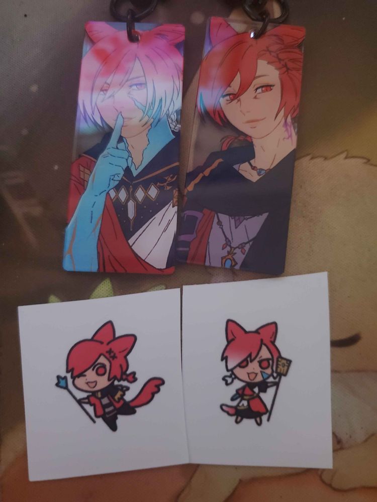 Raha keychains! One is the Exarch and the other is him post-ShB. Also two small and cute stickers of him as said versions.