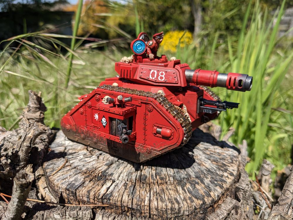 Bright red Leman Russ battle tank festooned with grisly trophies.