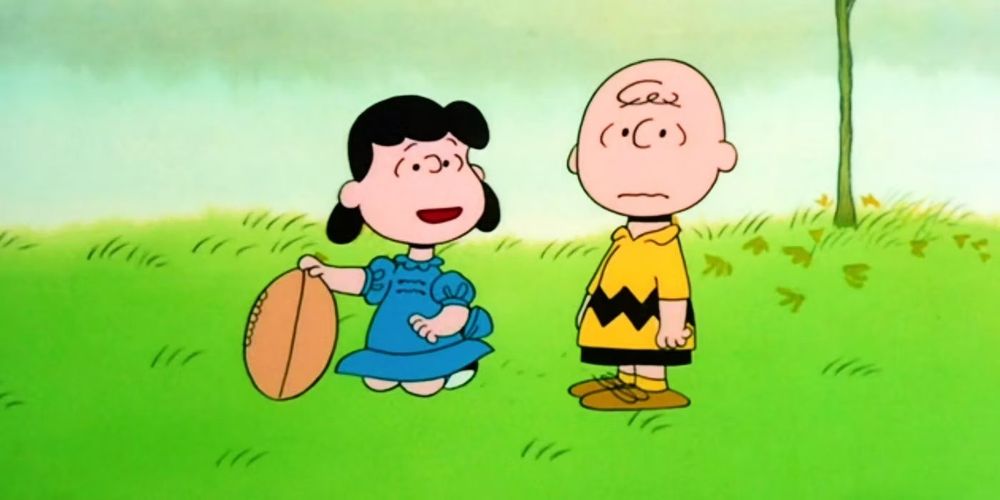 From the Peanuts comic strip: Lucy holding a football while Charlie Brown looks with apprehension.