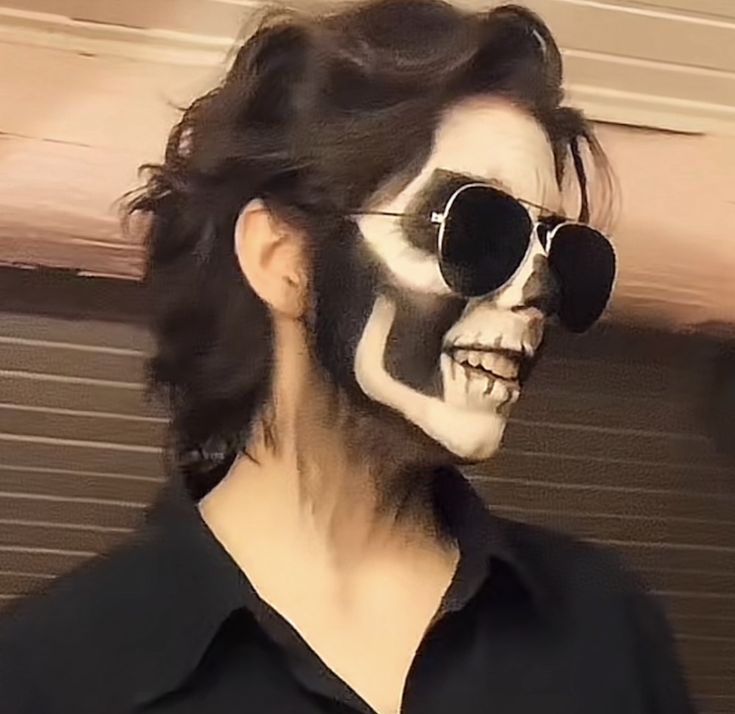 Photo of a person posed the same as the drawing, in aviators and skull makeup