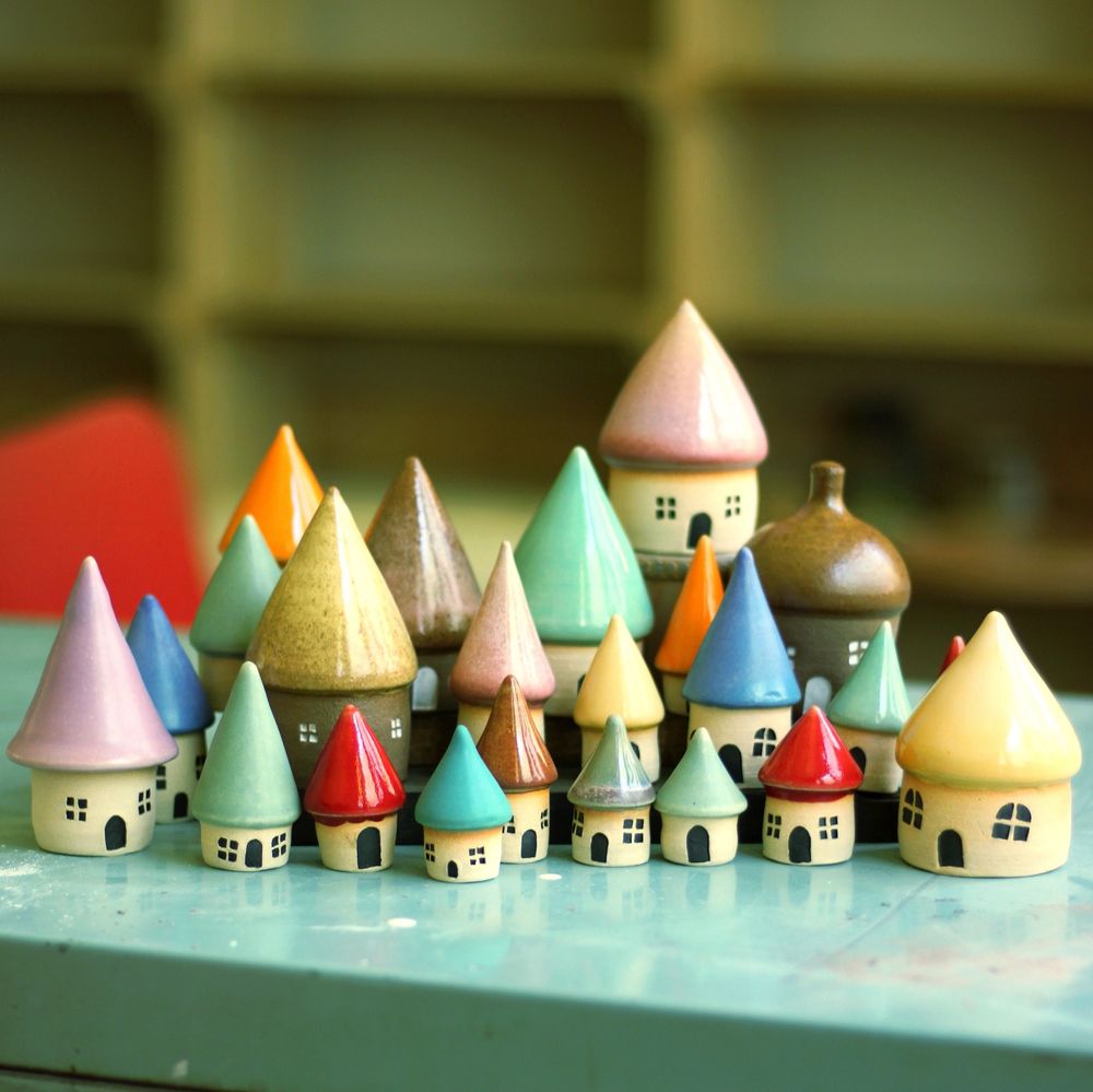 A small village of ceramic houses with different colored roofs, displayed on a turquoise metal desk