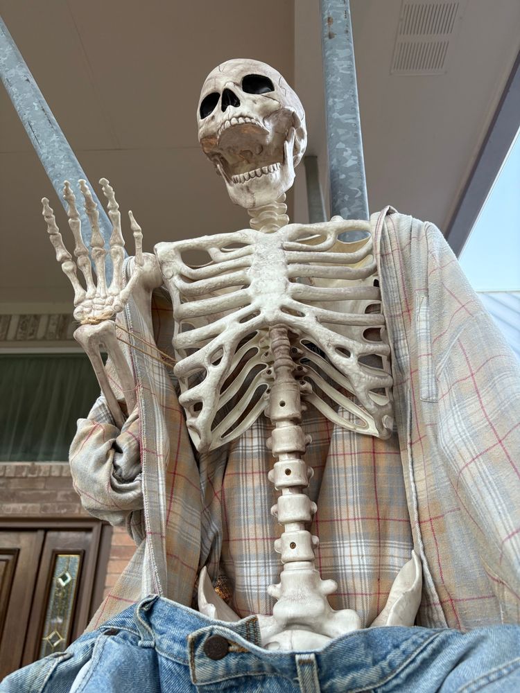 Half dressed skeleton waving with open jaws