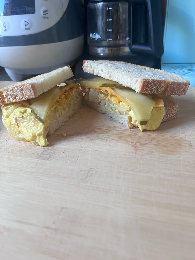 vegan egg sandwich with onions, pickles, and vegan cheese.