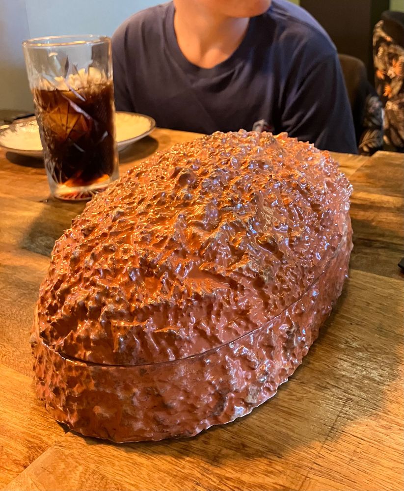Photo of a ceramic dish shaped like a croqueta on a dining table. 