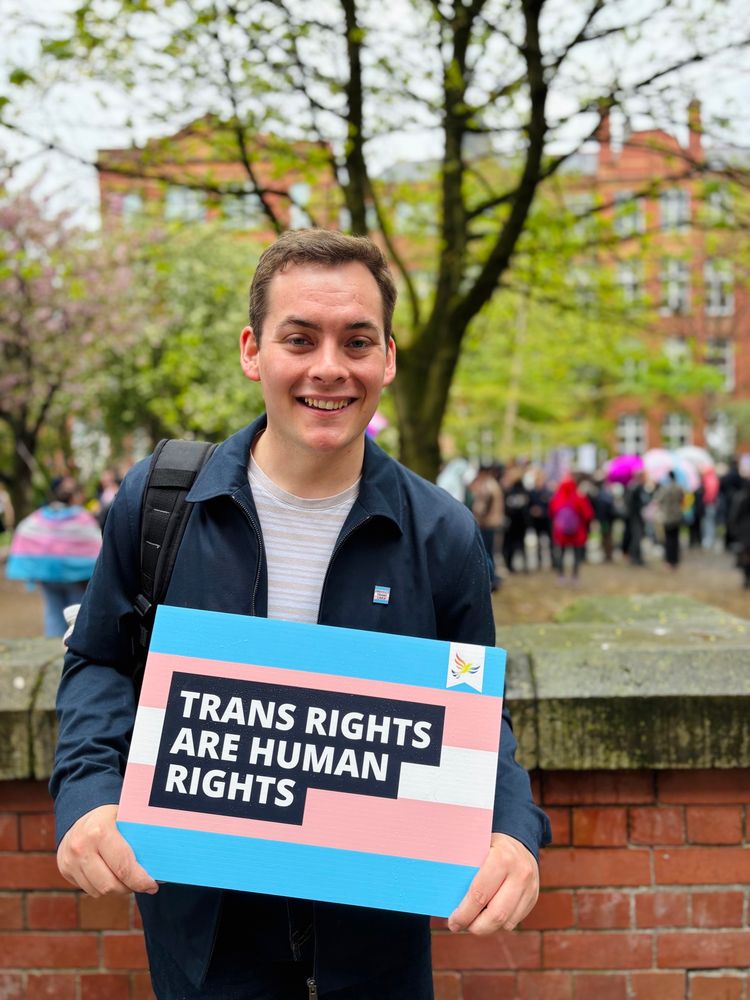 Luke stood outside Sackville Gardens holding a “Trans Rights are Human Rights” placard.