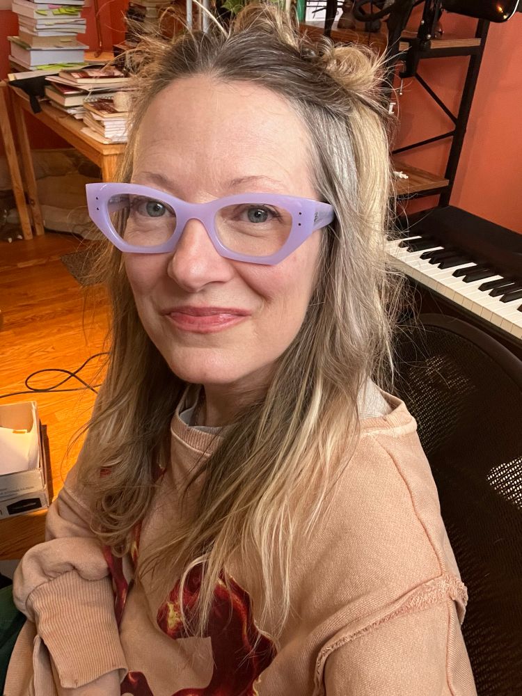 woman wearing glasses in front of a piano keyboard 