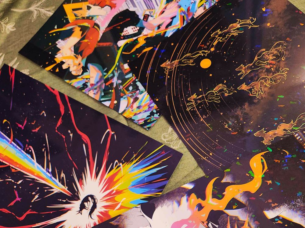 image is a photograph of an assortment of art prints featuring the artist's anthropomorphic characters as well as otherworldly animals.
