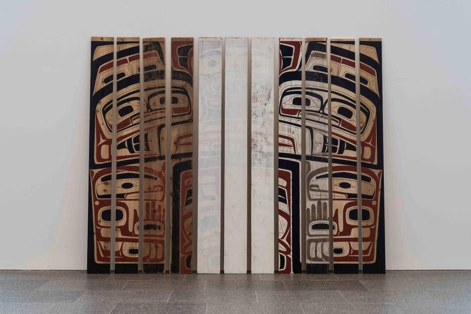 image is a photograph featuring the eleven plywood and cedar panels that make up Haida / Nisga'a artist Luke Parnell's "A Brief History Of Northwest Coast Design". The panels are decorated with traditional formline artwork. The four panels to the left progressively grow darker, obscuring the artwork. The three in the middle have been washed with a thick white acrylic paint, further obstructing the art. The four to the right have clear artwork on top of wood that fades from white to natural as it progresses from left to right. Photograph source: theglobeandmail.com #indigenousart #indigenoushistorymonth 