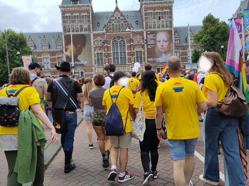 Mensen op de Pride March met shirts van Shell met een regenboog in de schelp 