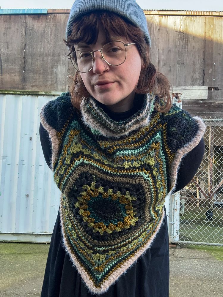 Human wearing a multi-colored crocheted wrap sweater 