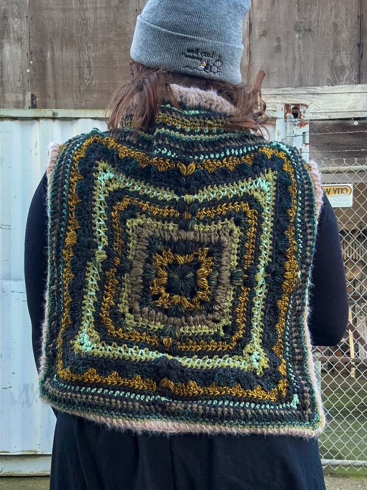 A human wearing a multi-colored crocheted wrap sweater 
