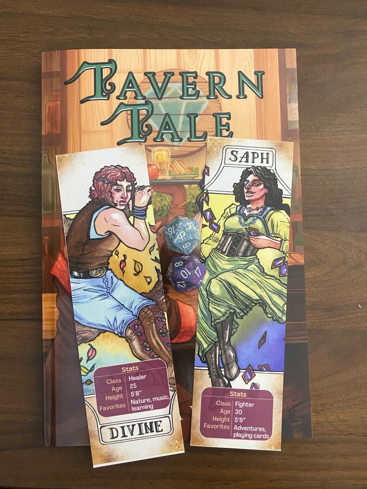 The image shows a book titled "Tavern Tale" with two character cards placed on top of it. The character cards feature illustrations of two different characters. The left card depicts a character named Divine, who is a healer, 25 years old, 5'8" tall, and enjoys nature, music, and learning. The right card depicts a character named Saph, who is a fighter, 30 years old, 5'9" tall, and enjoys adventures and playing cards. There are also two polyhedral dice (a d20 and a d12) placed between the cards.