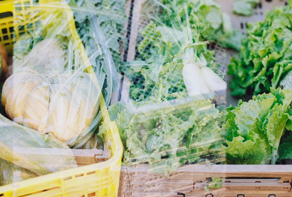 Accidental double exposure. The photograph shows crates of vegetables at a market.
Doble exposición accidental. En la fotografía se ven cajas con verduras en un mercado.