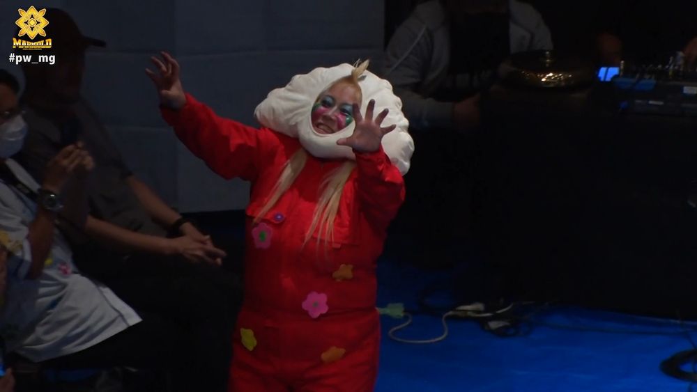 Megaton walks out smiling with her arms extended and her head wrapped in a big white gyoza-shaped pillow thing