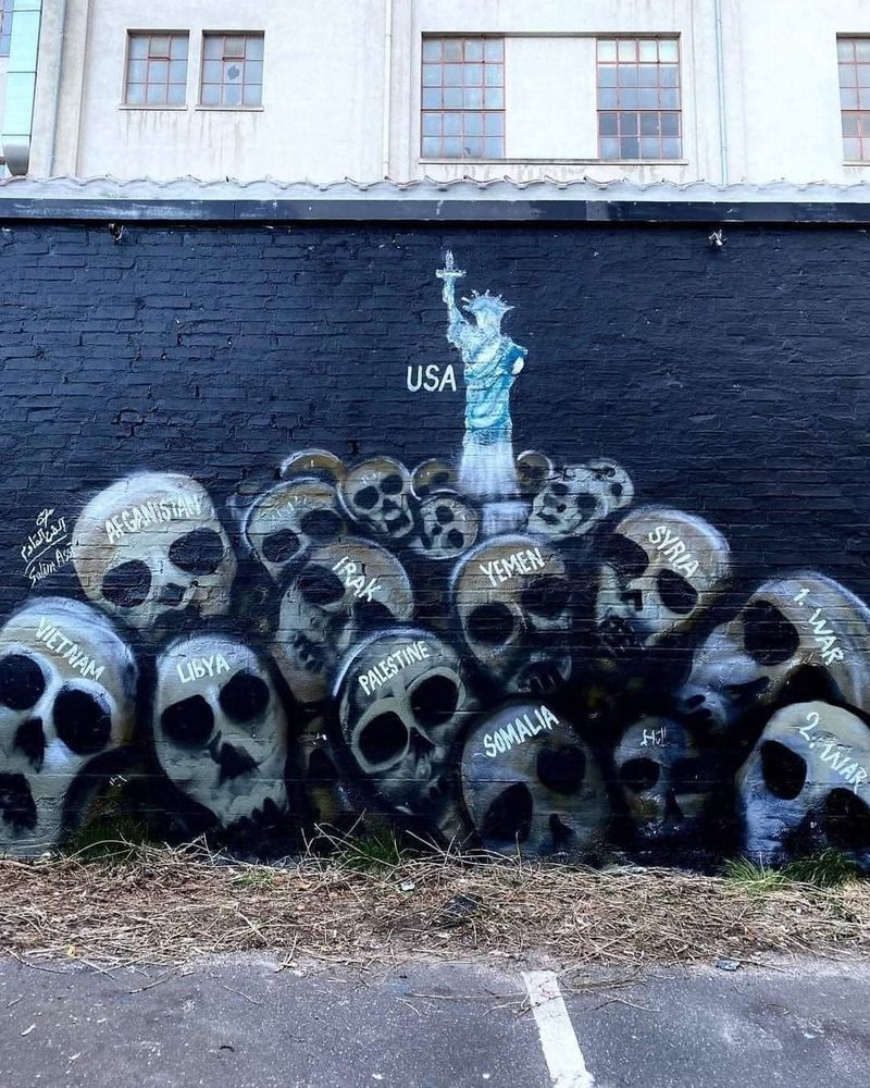 A mountain of skulls with the statue of liberty above them. 
They are labelled afghanistan, syria, iraq, yemen, palestine, vietnam, libya