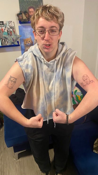 scout again but this time he's flexing and showing off two king of the hill tattoos- hank hill on their right bicep & dale gribble on the left bicep 