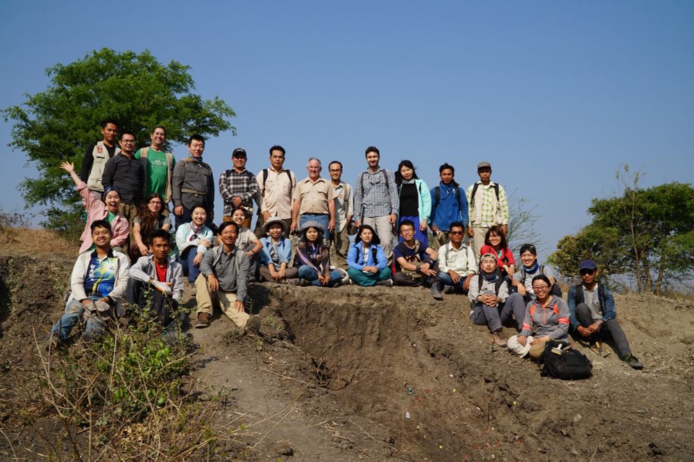 A group photo of around 25 people posing on a fault scarp formed by the Sagaing fault