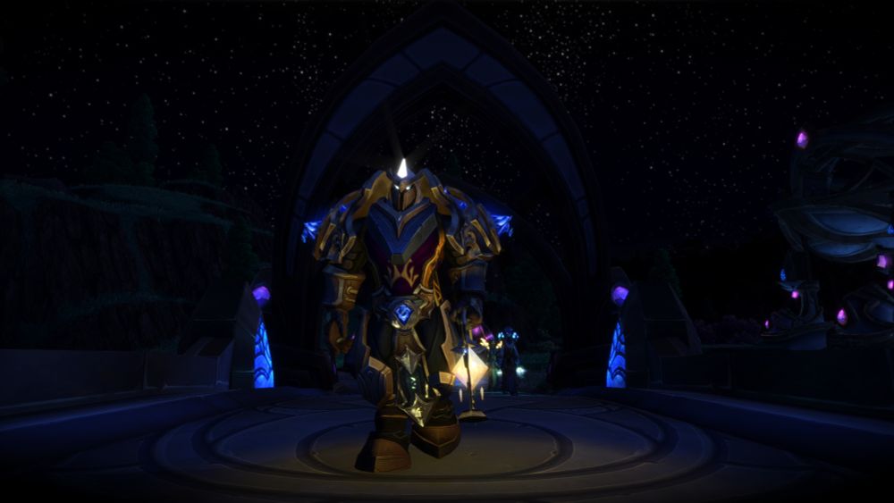 A screenshot from world of warcraft, showing Ibaaros the draenei death knight - they are dressed in heavy platemail primarily from Shadowlands raids, with shoulders and belt from the warlords of draenor paladin set. They carry a naaru-shaped light as they walk toward the camera.