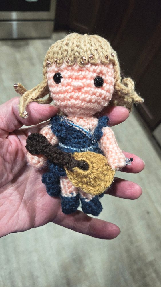 Crocheted Taylor Swift, holding guitar. Being held in my hand