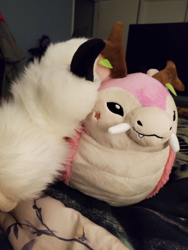 A Cherry blossom stuffed dragon receives pets from giant, puffy paws.