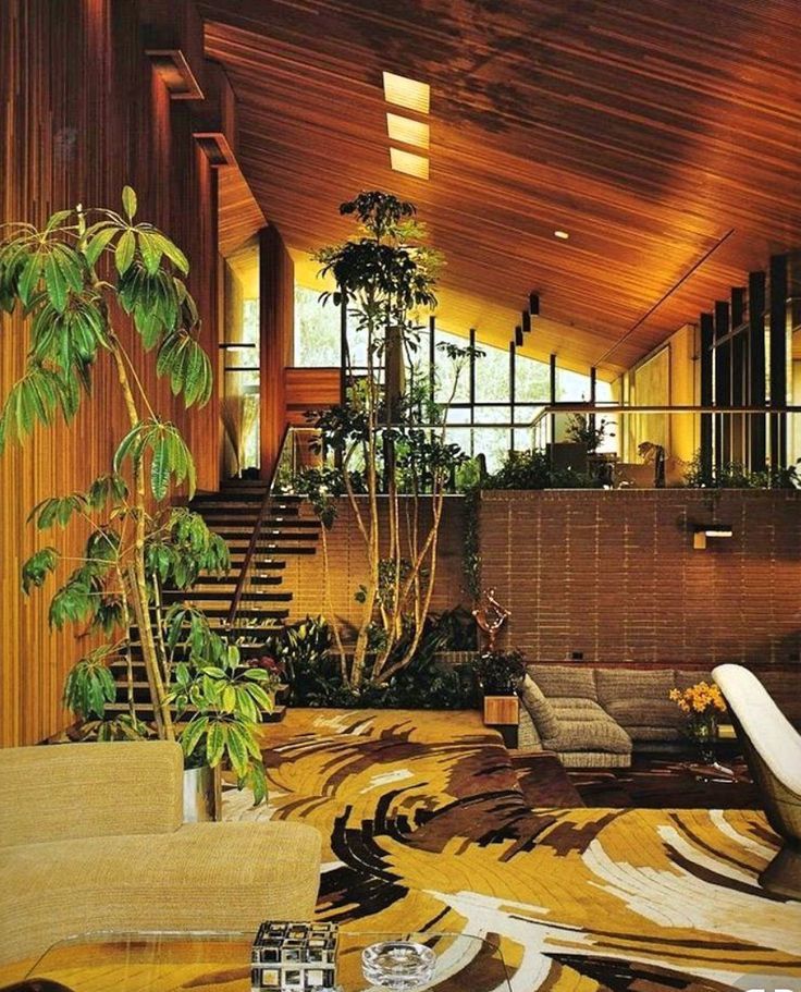The split-level California Modern cedar interior decorated in earth tones with high ceiling and tall plants throughout the space 
