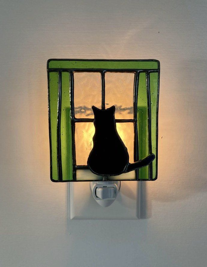 Stained glass (black cat looking through a window with green curtains) nightlight by glassbymeplus/Etsy 
Saint Charles, Missouri