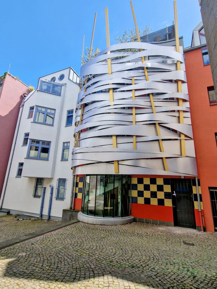 Ein Haus, dessen Fassade aussieht, als würde sie von Bändern und Holzstäben zusammengehalten. 