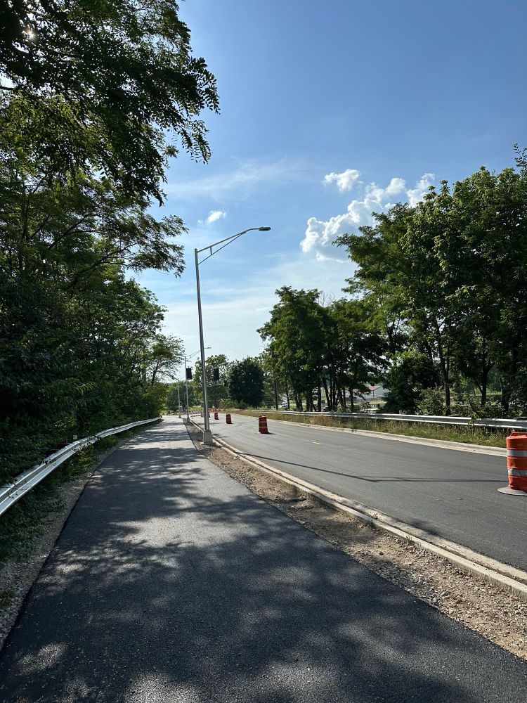 Looking west on Whittier St, away from the bridge over the railroad tracks. A 10’ wide shared use path has recently been paved with asphalt. The roadway has also been resurfaced. A temporary traffic signal remains in place.