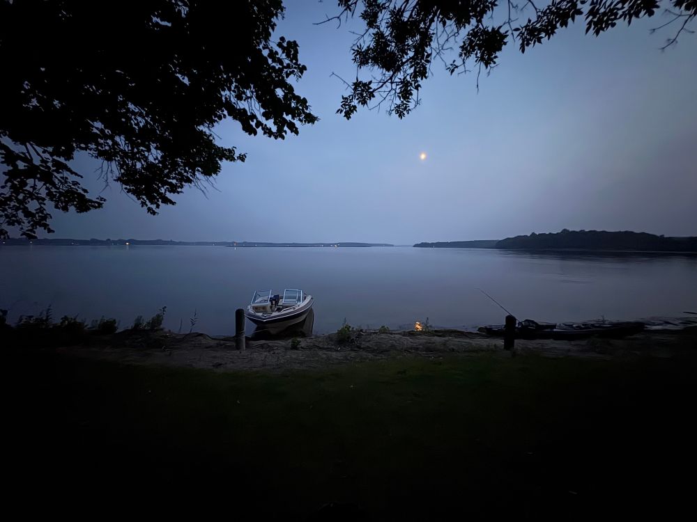 The moon in the wildfire smoke over a calm Lake 