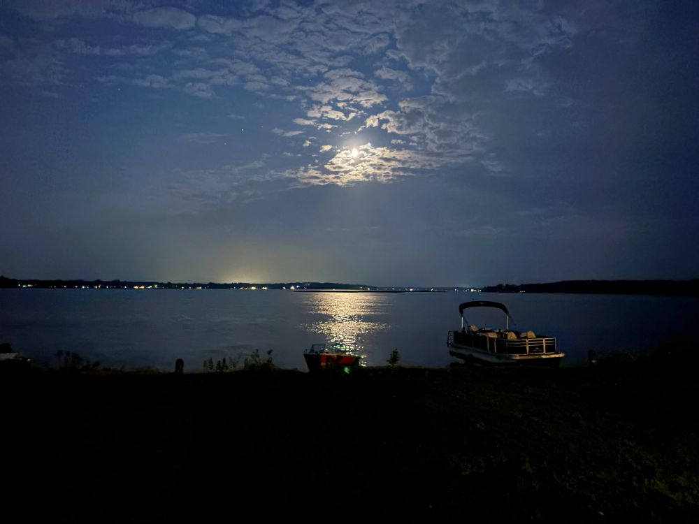 The moon and some clouds over a gently rippled lake. 