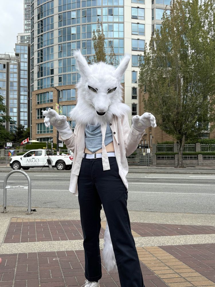 A photo of the same person, posing on the sidewalk with their paws held up and head tilted down menacingly.